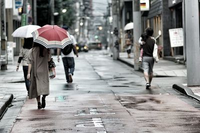 Rear view of men walking on street in city