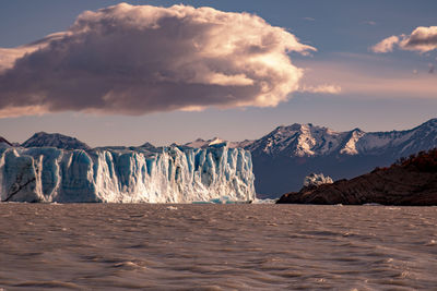 Scenic view of glacier by sea against sky