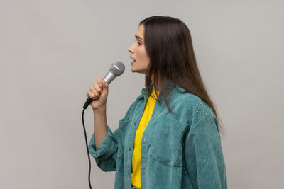 Side view of young woman holding microphone