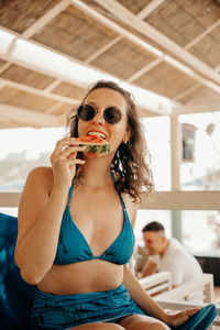 Portrait of a young woman sitting and eating watermelon