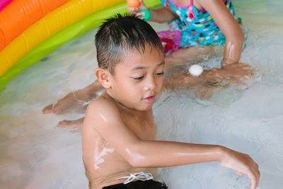 High angle view of siblings playing in wading pool