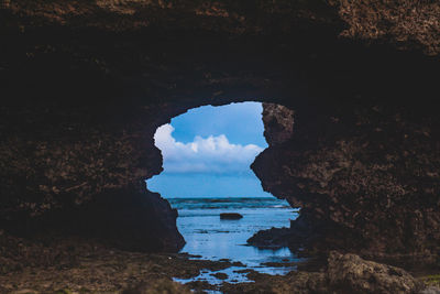 Close up of a rock object  with a natural arch  in the sea against sky