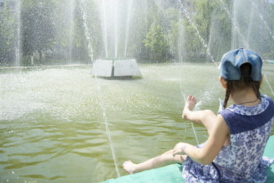 Rear view of man splashing water fountain in lake