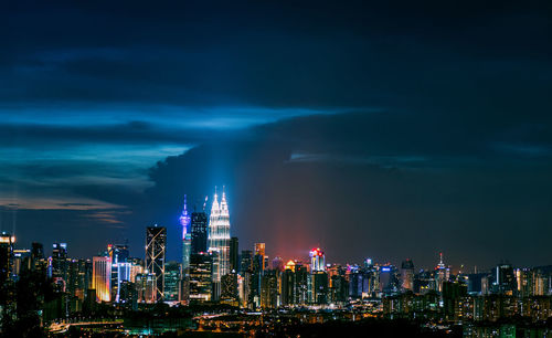 Illuminated buildings in city against sky at night