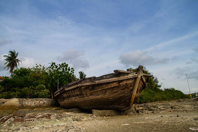 Abandoned boat on shore against sky