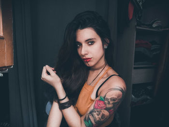 Portrait of beautiful woman with tattoo standing at home