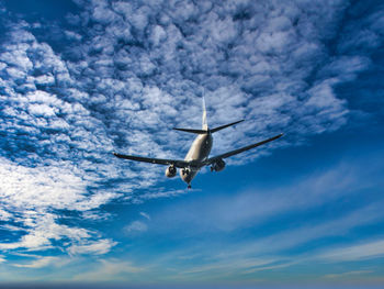 Low angle view of airplane flying against sky