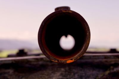 Close-up of rusty metal on field against sky