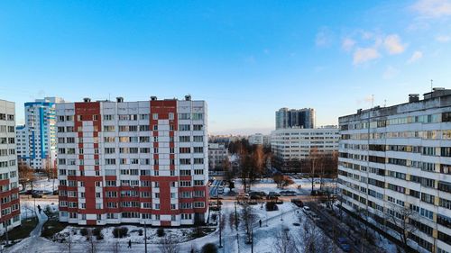 Buildings in city against clear blue sky during winter