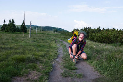Full length of woman sitting on land against sky