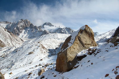 Snow-capped high-mountain ranges and glaciers of tuyuksu gorge with a large stone in winter