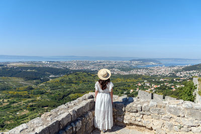 Rear view of woman standing on hill at klis fortress above city of split in croatia