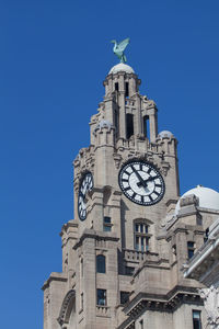 Low angle view of clock tower against blue sky