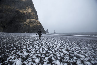 Man walking on snow covered beach