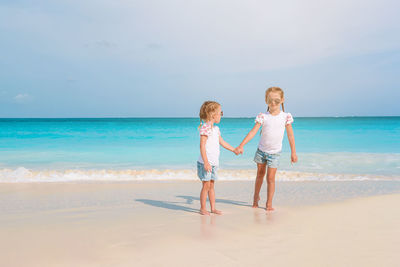 Full length of siblings on beach against sky