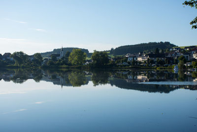 Scenic view of river by houses against clear blue sky