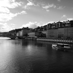 Boats moored at harbor in city against sky