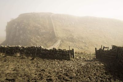 Panoramic view of landscape against mountain range in foggy weather