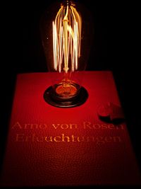 Close-up of illuminated light bulb against black background