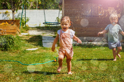 Full length of boy playing with dog on grassy field