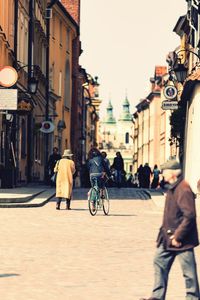 Rear view of people walking on street amidst buildings