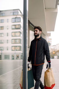 Full length of young man delivering grocery bags in building