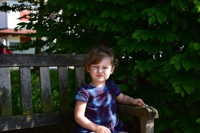 Portrait of cute girl sitting on bench at park