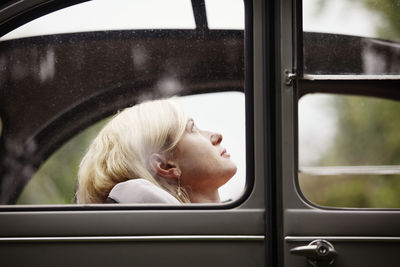 Woman looking up while sitting in vintage car