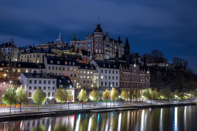 Buildings by river against sky