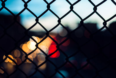 Close-up of chainlink fence against sky during sunset