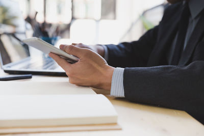 Midsection of man using digital tablet on table