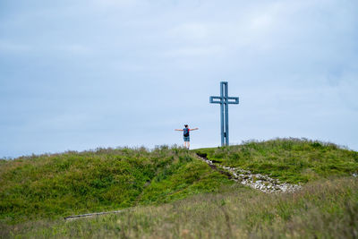 Woman standing next to crucifix on alpine footpath in the austrian alps, loser mountain region