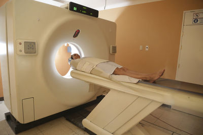 Patient lying at entrance of cat scan machine in medical examination room