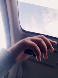 Close-up of hand holding airplane window