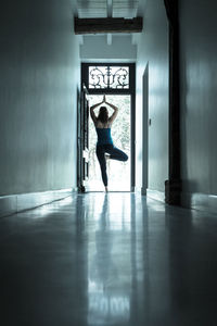 Full length portrait of woman sitting at entrance of building