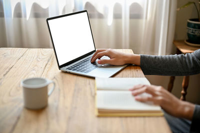 Midsection of woman using laptop on table