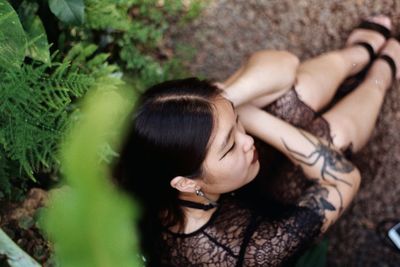 High angle view of thoughtful young woman sitting on field