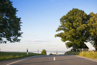 Road by trees against clear sky