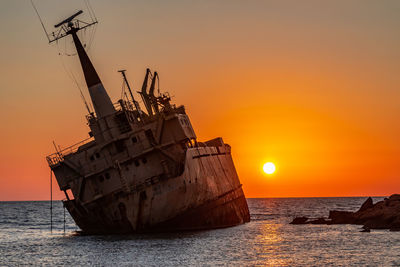 Traditional boat at sea against sky during sunset