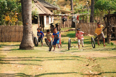 Group of people playing on field against trees