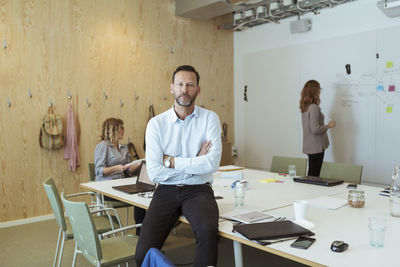 Portrait of confident businessman with colleagues in board room at office