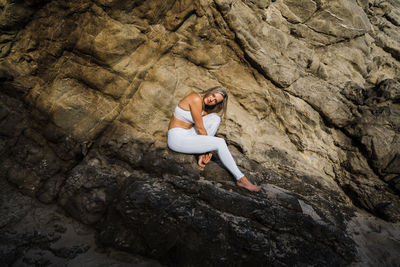 Young woman sitting on rock in the sunshine