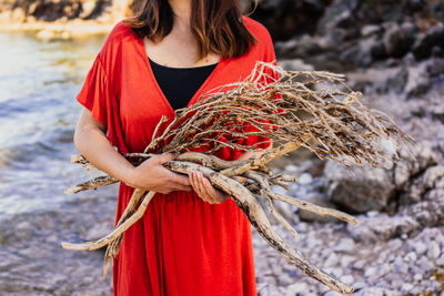 Midsection of woman holding red while standing on land