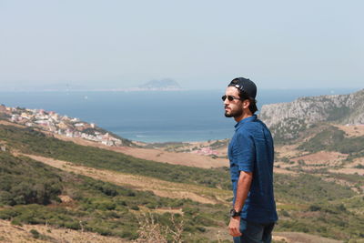 Young man looking at sea against sky