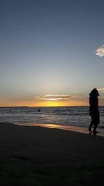 Silhouette man on beach against sky during sunset