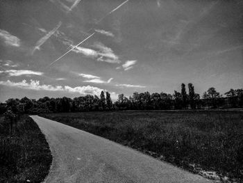 Road by agricultural field against sky