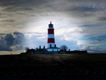 Low angle view of lighthouse by building against sky