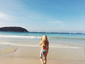 Rear view of woman at beach against sky