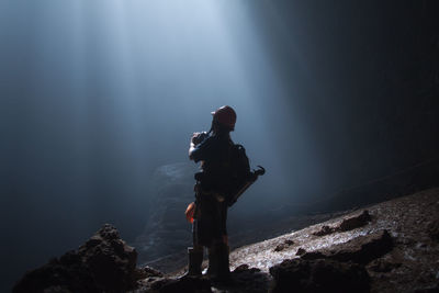 Low angle view of man standing on rock against sky