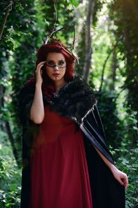 Portrait of young woman standing against trees in forest